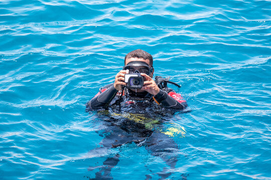 Underwater photographer videographer scuba dives on surface of sea. underwater photography and videography concept