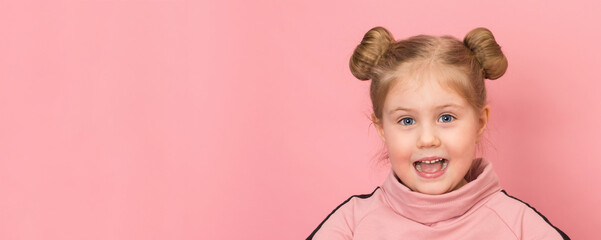 Smiling excited happy funny girl wearing hair buns close up portrait on pink background. People childhood lifestyle concept. Copy space.
