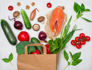 Healthy food background. Vegetables greens and salmon in paper bag on white background. Shopping food supermarket or food delivery concept.