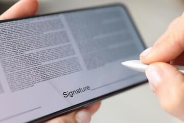 Person puts signature with stylus on contract screen of smartphone