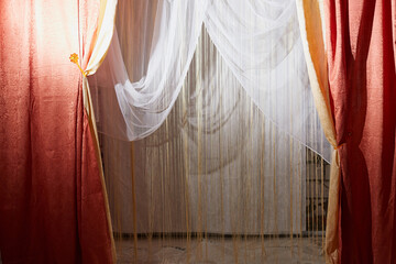 Red stage curtain with light and shadow and white curtains in the background