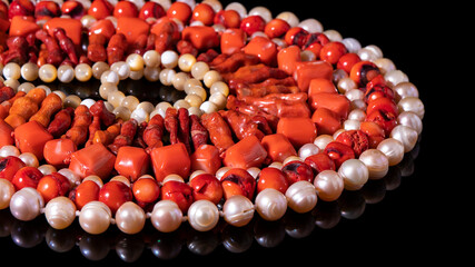 Shiny red coral beads of different shape and nacreous pearl necklaces   laid out in a circle on a...