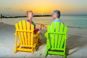 Romantic older couple at the beach with beach chairs having drinks, champagne, at sunset