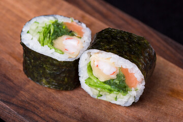 Delicious fresh rolls with red fish, awakad, cream cheese, lettuce, sesame seeds, on a wooden worthy.
