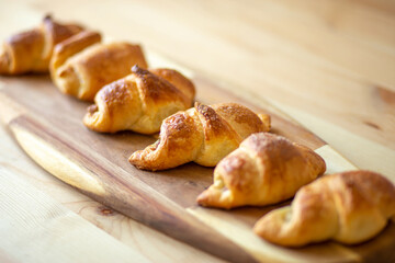croissant, homemade fresh baked goods lies on a beautiful bamboo board on a wooden table