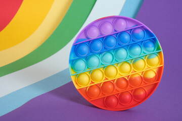 trend toy antistress pop it on a rainbow background, fidget toy, popping bubbles and calm down, development of the motor skills of hands and fingers
