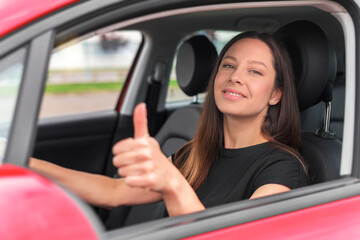 Fototapeta na wymiar Car. Beautiful woman in the car shows thumbs up. Happy brunette in the car.