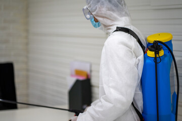 Asian social medical worker in PPE protective suit using disinfection spray to protect virus pandemic. 