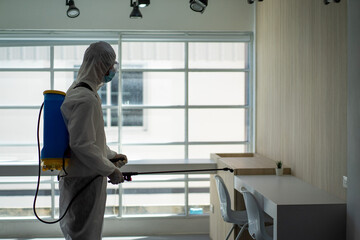 Asian social medical worker in PPE protective suit using disinfection spray to protect virus pandemic. 