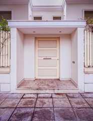 contemporary house front entrance white door by the sidewalk