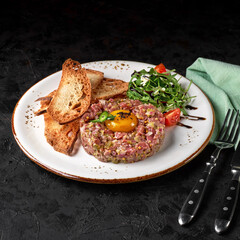 Steak Tartare with bread toasts served on a black background. appetizer or snack. menu