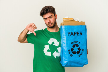 Young caucasian man man recycling cardboard isolated on white background showing a dislike gesture, thumbs down. Disagreement concept.