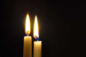 two burning candles on a black background