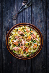 Fusilli with roasted salmon on wooden table 