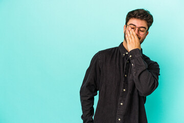 Young caucasian man isolated on blue background laughing happy, carefree, natural emotion.