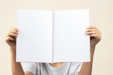 Kid hands holding open notebook with blank white pages in front of him