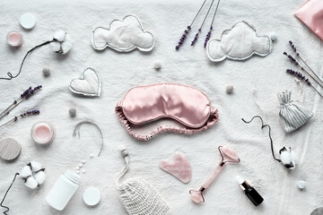 Healthy night sleep flat lay. Pink sleep mask, face stone roller, Gua Sha stone and essential oil....