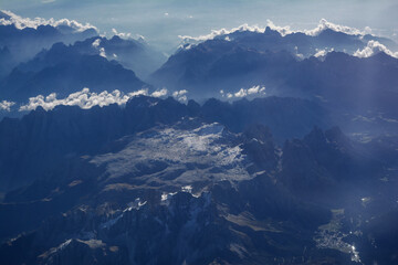 Aerial view of snowy mountains and clouds, opposite the sunlight