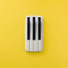 2021 Mobile smart phone with piano keys, isolated on illuminating yellow background. Musical, fun,...