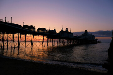 Fototapeta premium Golden Sunrise over the sea with clear skies and a silhouette of a pier