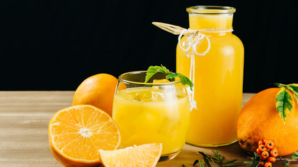 orange juice for a hot day, on a black background and a wooden table