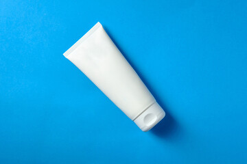 White tube with cream on a blue background, place for an inscription