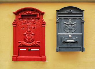 Classic old red and black Italian postboxes on a yellow painted stucco wall, Florence, Italy