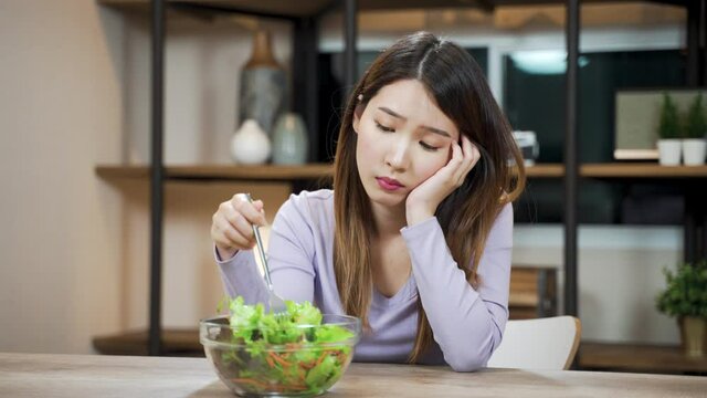 Bored Asian woman dislike to eats vegetable salad. female want to quit vegetarian or healthy eating