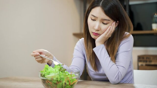 Bored Asian woman dislike to eats vegetable salad. female want to quit vegetarian or healthy eating