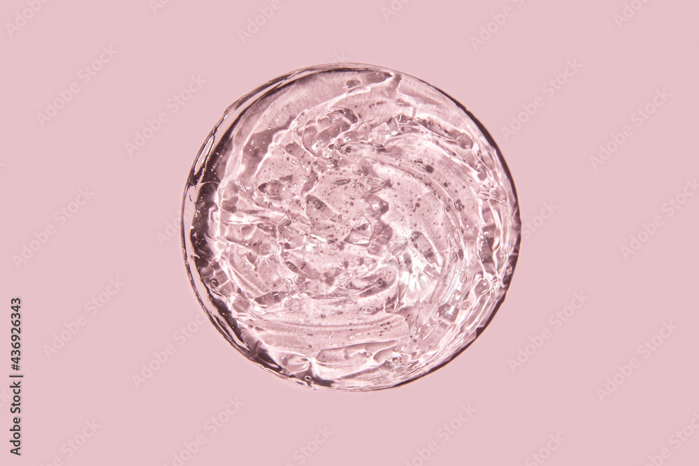 Wall mural close-up transparent cosmetic gel in glass isolated on pink background. make-up and cosmetics textur