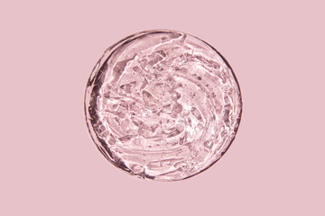 Close-up transparent cosmetic gel in glass isolated on pink background. Make-up and cosmetics texture background, skincare product