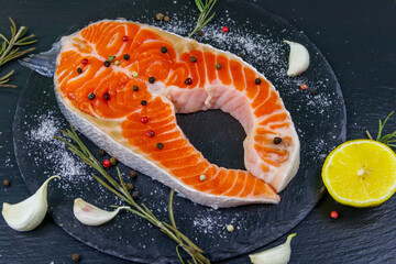 Raw salmon steak with spices on black slate