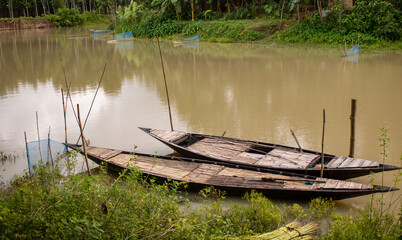 Bangladesh is a riverine country. A calm clear beautiful small river. There are two boats tied up...