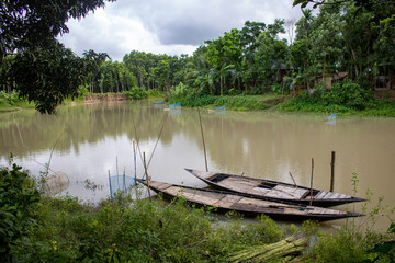 Bangladesh is a riverine country. A quiet beautiful small river. There are two boats tied up at the wharf.