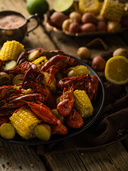 In the photo, corn and boiled crayfish. In the background there is a photo of lemon, vegetables. Close-up. Macro photography. There are no people in the photo. Bright colors.