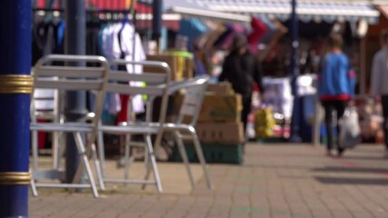 Shoppers walking in a market place with cafe