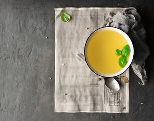 Broth recipe background. Chicken broth in a white bowl with fresh basil and a spoon on old paper with space for text. Top view. Flat lay