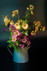 Flowers in a metal jug on a black background