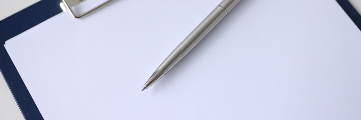 Ballpoint pen lying on clipboard with blank document closeup