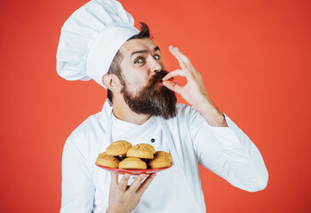 Happy bearded chef, cook or baker gesturing excellent. Male chef with plate of oatmeal cookies showing sign delicious.