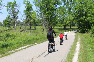 Mother with her two sons riding bicycles on the North Branch Trail at Miami Woods in Morton Grove, Illinois