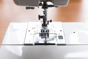 Needle presser foot with thread of industrial sewing machine for sew cloth close-up.