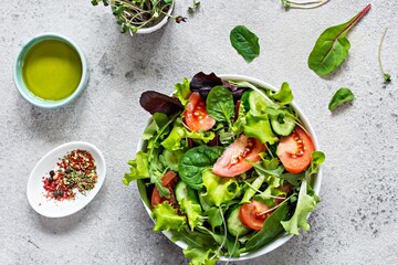 Fresh salad with fresh vegetables, ripe tomatoes, cucumber, lettuce and microgreen  in a bowl on a...