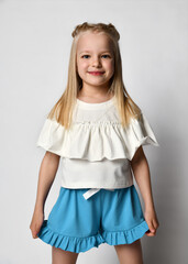 Portrait of a stylish little girl in summer clothes on a white background. Smiling cheerful blonde...