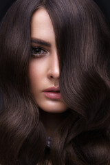 Fototapeta premium Beautiful brown-haired girl with a perfectly curls hair, and classic make-up. Beauty face and hair.