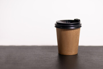 Disposable coffee cup for cafe on the table. Brown cardboard mockup of eco friendly coffee cup isolated on white background with place for text. Disposable Plastic and Paper Hot Drinks Template