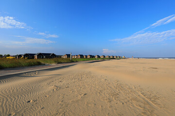 Wooden houses and sand dunes against a blue sky background