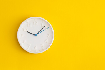 White wall Clock on yellow background.