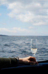 Person holding a glass of champagne while being out at sea on a boat. Photo taken in the archipelago in Sweden.