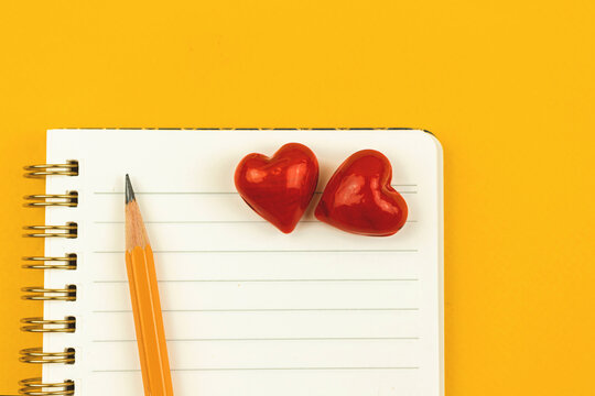 Couple love, school first love concept with notepad and two red hearts on it, pencil, yellow background, top view and copy space photo